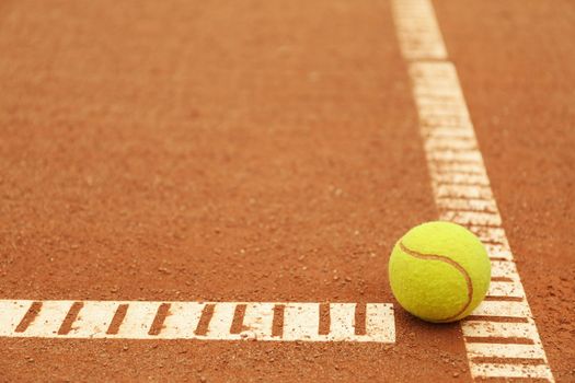 Light green tennis ball on clay court, space for text