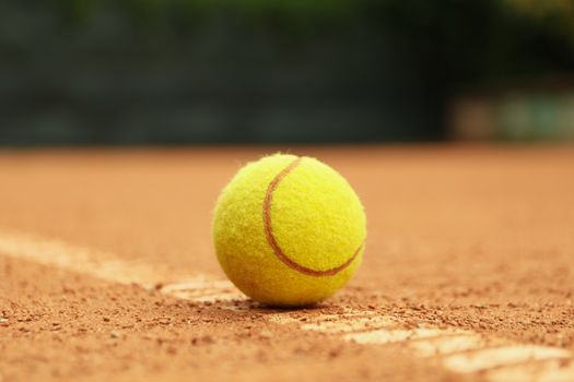 Light green tennis ball on clay court, close up