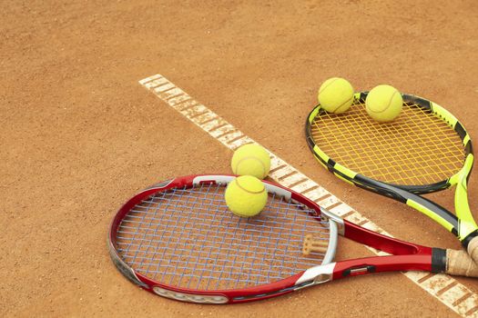 Tennis racquets with tennis balls on clay court