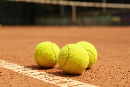 Light green tennis balls on clay court