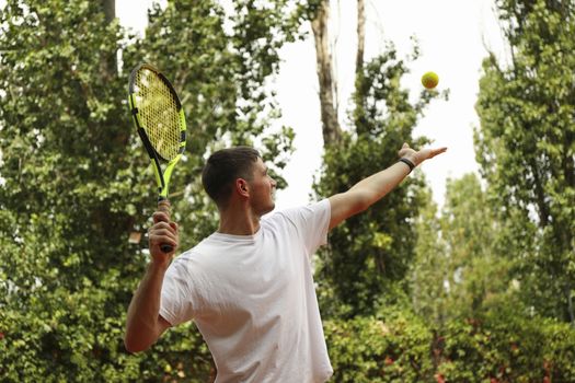 Young man in white t-shirt serve the tennis ball