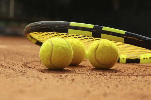 Racket and tennis balls on clay court