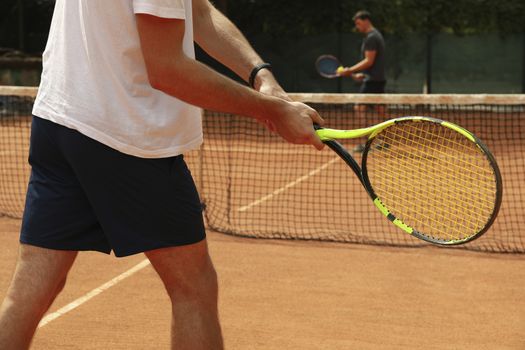 Two men playing tennis on clay court