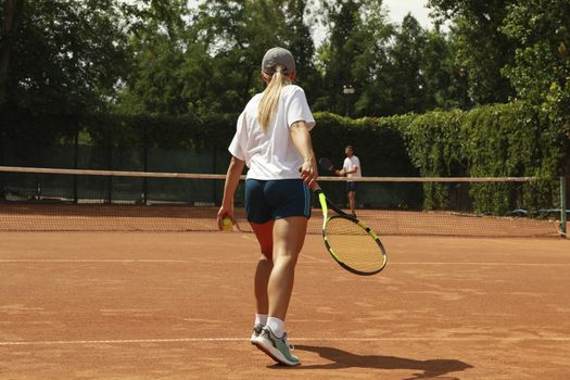 Two people playing tennis on clay court