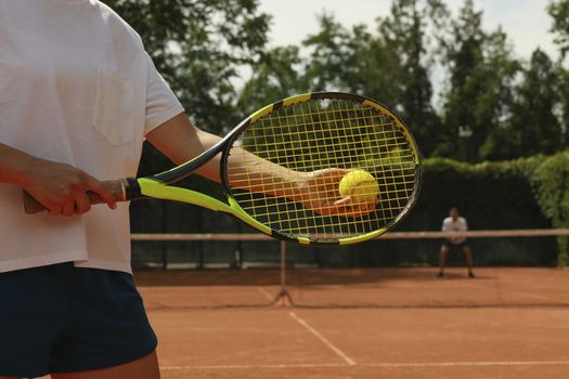 Woman hold racket and tennis ball on clay court