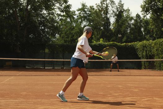 Two people playing tennis on clay court