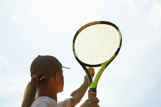 Young woman in white t-shirt serve the tennis ball