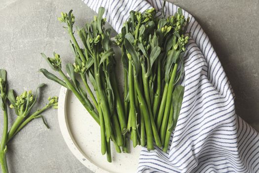 Tray with broccolini and napkin on gray background