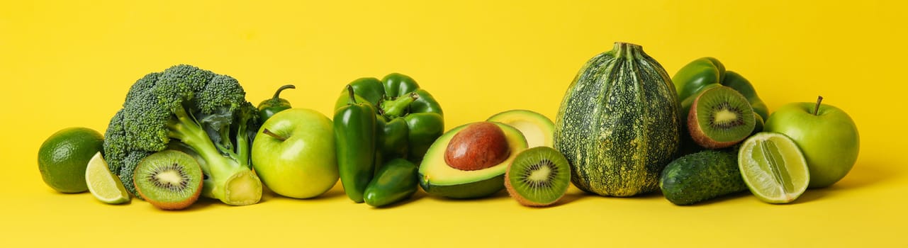 Green vegetables and fruits on yellow background