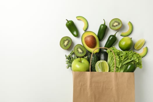 Paper bag with vegetables and fruits on white background