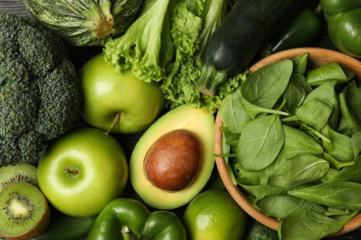 Green vegetables and fruits on wooden background, top view