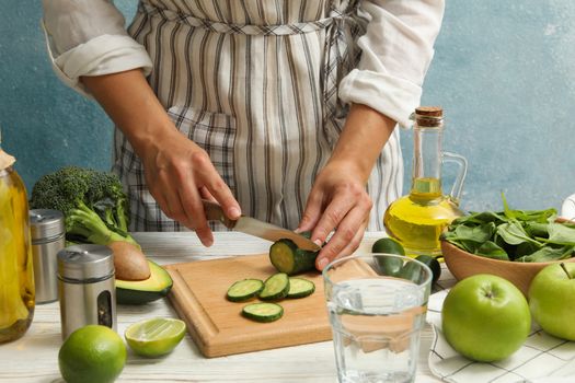 Woman cutted cucumber on white wooden table