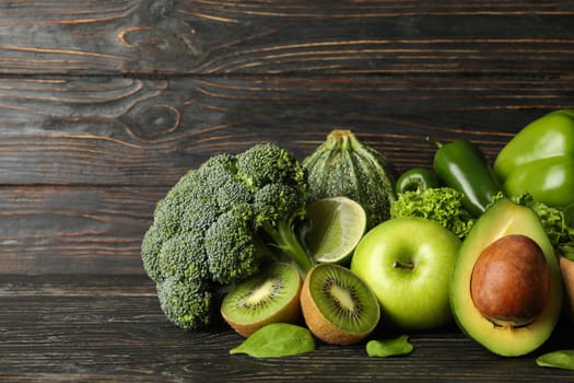 Green vegetables and fruits on wooden background