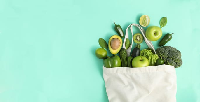 Bag with vegetables and fruits on mint background