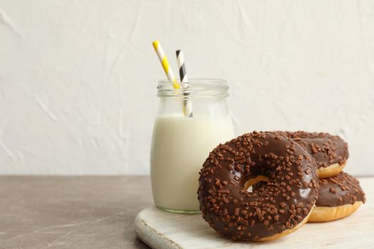 Jar of milk and tasty donuts on gray table