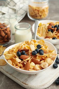 Concept of breakfast with muesli, berry, nut and milk on gray table