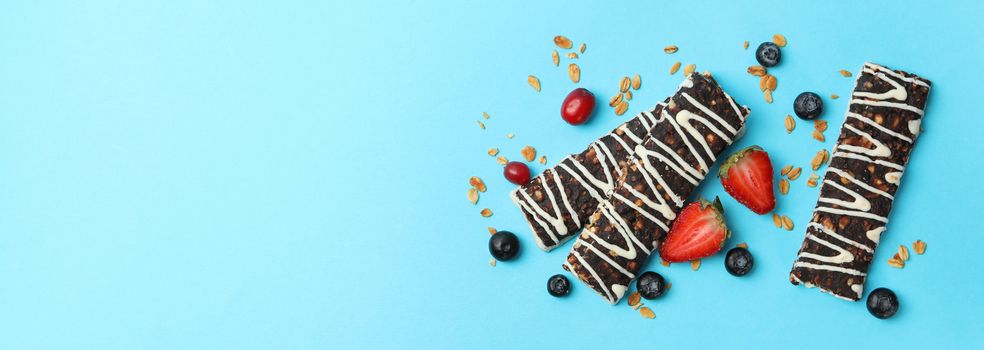 Tasty granola bars on blue background, top view