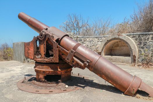 Old rusted cannon from World War II. Japanese cannon Meriam Jepang in a stone fortification on the island of Lombok in Indonesia. Color image of an old cannon on a sunny day.