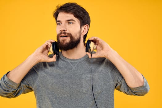 Man in headphones listens to music technology lifestyle fun people yellow background. High quality photo