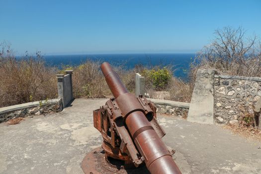 Back view from ancient cannon heading to the sea. These type of cannon were used in order to protect them from invaders in south of Brazil. Concept of protection and power. Cannon on sea background.