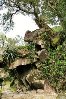Stone arch with rocks in a Leafy garden with large trees in Sintra, Lisbon