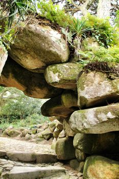 Stone arch with rocks in a Leafy garden with large trees in Sintra, Lisbon