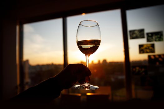 Wine glass in a hand over sunset