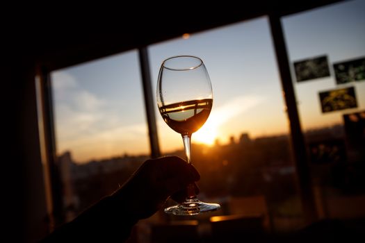 Wine glass in a hand over sunset