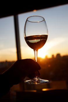 Wineglass over sunset. Window and city on the background