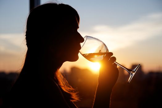 Girl drinking from a glass at sunset