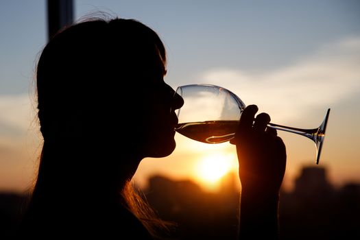 Girl drinking from a glass at sunset