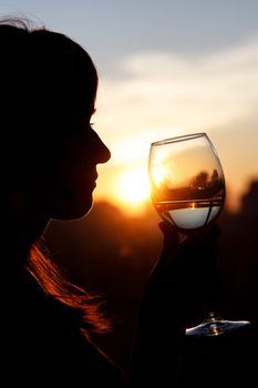 Girl drinking from a glass at sunset