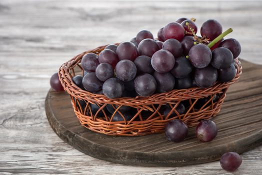 Delicious bunch of grapes fruit on a plate over wooden table background, close up.