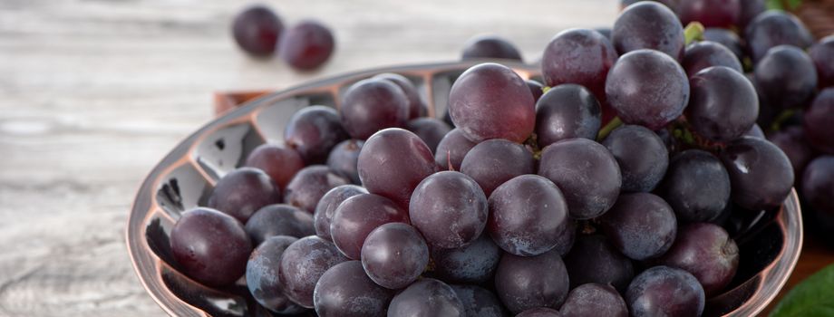 Delicious bunch of grapes fruit on a plate over wooden table background, close up.