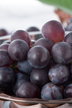 Delicious bunch of grapes fruit on a plate over wooden table background, close up.