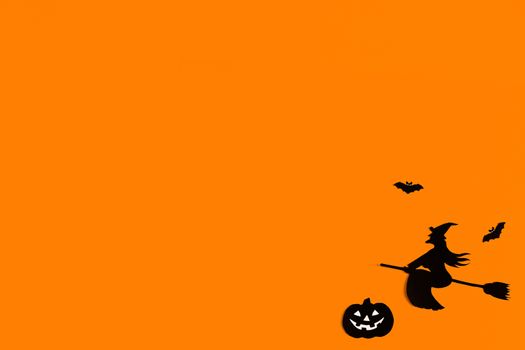 Silhouettes of a flock of bats and a witch flying on a broom made of black paper on an orange background. Halloween greeting template with copy space. Flat lay for your design. ready-made template.