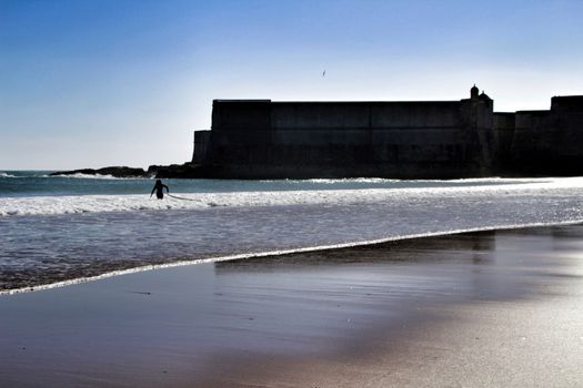 Beautiful beach called Praia da Torre in Lisbon, Portugal, in a sunny day of Spring. Surfers playing with the waves.