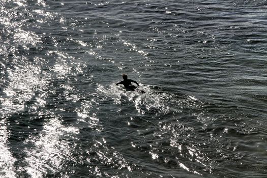 Surfer in the Beautiful Azarujinha beach with rock formations in Estoril, Lisbon, Portugal, in a sunny day of winter