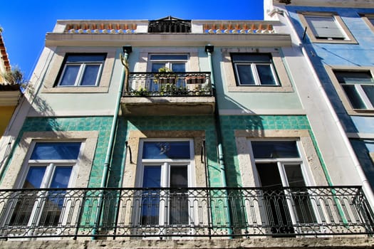 Old colorful and majestic tiled facades with vintage streetlight in Lisbon streets in Spring.