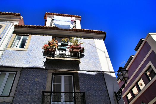 Old facade of typical Lisbon house with hanging clothes in clothesline.