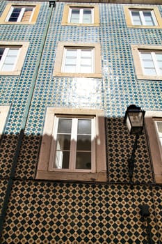 Old colorful and majestic tiled facades with vintage streetlight in Lisbon streets in Spring.