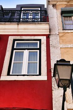 Old colorful and beautiful facades with vintage streetlight in Lisbon streets in Spring. Clothesline in the facade with hanging clothes