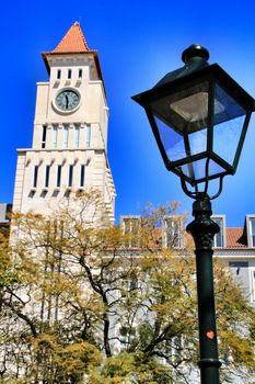 Beautiful building with a tower with clock in Dom Luis I square in Lisbon. Vintage Lamp post in the foreground.