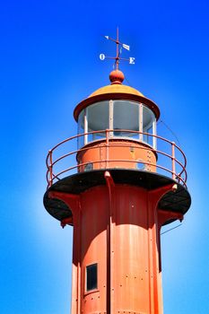 Red lighthouse in the port of Almada village in Lisbon on a sunny day of winter. 