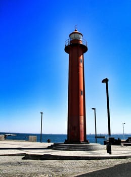 Red lighthouse in the port of Almada village in Lisbon on a sunny day of winter. 