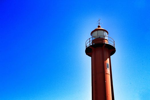 Red lighthouse in the port of Almada village in Lisbon on a sunny day of winter. 
