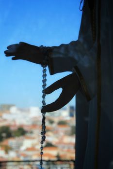 Image of the Virgin Mary hands holding a rosary in Nossa Senhora Do Monte viewpoint in Lisbon in a sunny day of winter