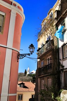 Old colorful and beautiful facades with vintage streetlight in Lisbon streets in Spring. Clothesline in the facade with hanging clothes