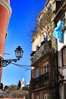 Old colorful and beautiful facades with vintage streetlight in Lisbon streets in Spring. Clothesline in the facade with hanging clothes