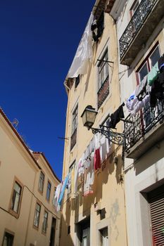 Old colorful and beautiful facades with vintage streetlight in Lisbon streets in Spring. Clothesline in the facade with hanging clothes
